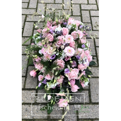 Rouwarrangement van zacht roze en witte bloemen met paars-blauwe accenten in ovale vorm